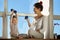 Young woman with her child holding a dumbbell and doing sports. Her daughter with a proud expression lifts the dumbbell