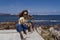 Young woman and her cute spanish water dog outdoors enjoying together on a sunny and windy day. Woman taking selfie with mobile