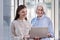 Young woman and her elderly boss working on laptop together