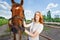 Young woman with her horse next to enclosure fence