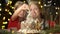 A young woman with her little daughter sprinkling powdered sugar on gingerbread house