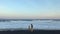 A young woman and her little son on an ocean coast with black volcanic sand. Shot on a phone