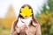 Young woman hides face with autumn yellow maple leave.