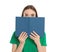 Young woman hiding behind book on white. Reading activity