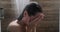 Young woman hiding face with hands and crying while taking shower