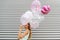 Young woman hiding her face behind pink balloon over striped background