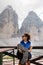 Young woman hiker resting near famous rock formation Tre Cime