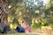 Young woman hiking in countryside. Girl resting under olive tree. Concepts of adventure, extreme survival, orienteering.