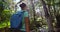 Young Woman Hiking in Forest. Active healthy woman with a backpack waking in wood. Female traveler walks in forest, rear