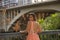 Young woman, Hispanic, beautiful, brunette, wearing an elegant salmon-colored dress, leaning on a railing looking over her