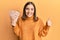 Young woman holding 50 turkish lira banknotes smiling happy and positive, thumb up doing excellent and approval sign