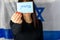 Young Woman Holding Ballot Front Of Face on Israeli Flag Background.Hebrew text I Voted on voting paper.