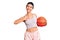 Young woman holding basketball ball pointing finger to one self smiling happy and proud