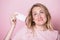 Young woman holding blister pack of pills smiling studio shot on pink background