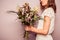 Young woman holding bouquet of dead flowers