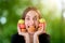Young woman holding a bunch of colorful macaroons around her face and with on ein her mouse on blurred background, close-up plan