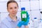 Young woman holding a chemical bottle with a green liquid in her hands text on the label e-fuel Biofuel chemical laboratory