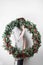 Young woman holding christmas large wreath in hands in light, seasonal holidays, rustic theme, adorning