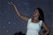 Young woman holding defocused Star. Woman under starry night. Woman in white long dress looking to starry night.
