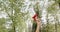 Young woman holding diploma with red stripe, raising hand, glad, happy outdoors.