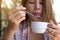 Young woman holding drinking coffee using spoon blowing hot coffee before drinking in the morning at home..Asian girl drinking
