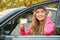 Young woman holding driving license near car