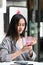 Young woman holding glass of raspberry refreshing drink while sitting at cafe.