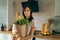 Young woman holding groceries paper bag in the kitchen home