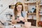 Young woman holding handmade earthenware over table while sitting in studio