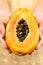 Young woman holding in hands half of ripe juicy papaya, close up