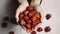 Young woman holding heap of red berries in hands. Fresh healthy vegan dietary food for spring detox. Fruits background. Clean