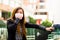 Young woman holding his protective mask with her hand on the street in the city with air pollution, asking for a taxi