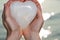 Young woman holding polished cream white carved Onyx Heart in her hands at the sunrise in front of the lake. Love, Romance