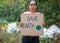 The young woman holding `Save The Earth` Poster showing a sign protesting against plastic pollution in the forest. The concept of