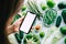 Young woman holding smartphone with white screen mock-up, in front fresh vegetables on the table. Healthy nutrition menu, or