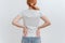 A young woman holding on to her back  in pain against a white background. Back problems, kidney problems. Spine osteoporosis