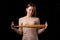 A young woman holds a bat in her hands and calmly looks into the camera. Black background. Self-defense, psychological protection