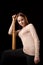 A young woman holds a bat in her hands and calmly looks into the camera. Black background. Self-defense, psychological protection