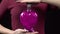Young woman holds a bottle with a love potion. Glass bottle in the form of a heart with pink liquid. Valentine`s Day is