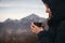 Young woman holds a Cup of hot tea in the hands against the background of mountains and warms his hands on a Cup of hot drink