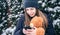 A young woman holds a teddy bear and a smartphone in her hands in snowy weather.