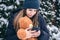 A young woman holds a teddy bear and a smartphone in her hands in snowy weather.