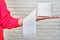 A young woman holds toilet paper in her hand, white brickwall background