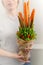 A young woman holds a vegetable bouquet consisting of carrots, pea pods, lettuce leaves, red pepper and aloe as a gift to a vegeta