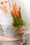 A young woman holds a vegetable bouquet consisting of carrots, pea pods, salad leaves, red pepper and aloe as a symbol of a health