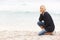 Young Woman On Holiday Kneeling On Beach