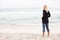 Young Woman On Holiday Standing On Winter Beach