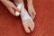 A young woman at home bandages her foot and lower leg with a bandage. Proper self-help with a bruised leg. Top view