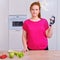 Young woman in home kitchen with dumbbells, vegetables and fruit. Concept of proper nutrition and sports in isolation during the