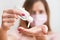 Young woman with home made pink cotton face mouth virus mask dropping anti bacterial alcohol rubbing gel on hand, detail to white